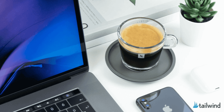A glass cup of espresso on a saucer sits on a white desk next to a laptop, iPhone, AirPods case, potted plant, and notebook—perfect for planning how to use Pinterest to rapidly grow your email list. "tailwind" appears in the bottom right corner.