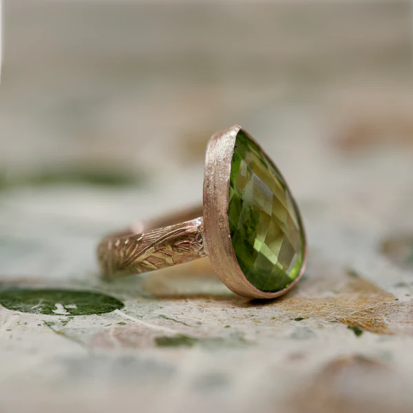 Photo of a ring with a large yelllow-green stone in a teardrop shape.