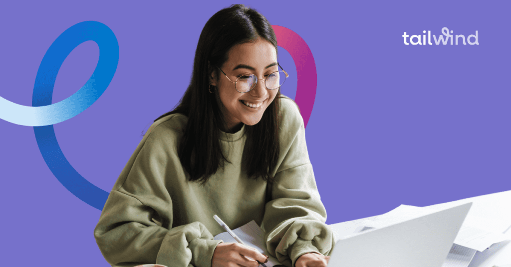 Smiling woman sitting at a desk working on her laptop on a purple background with the Tailwind logo.