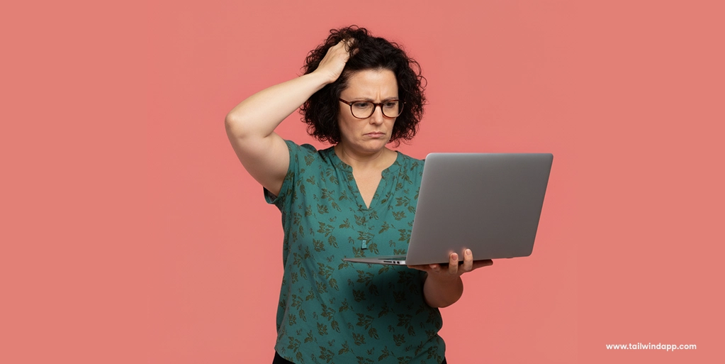 Frustrated woman holding a laptop and scratching her head, representing confusion over a Pinterest impressions drop.